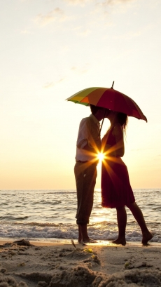 沙滩伞下亲吻的情侣